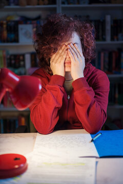 Teenage girl studying for exams at night with desk lamp and notes
