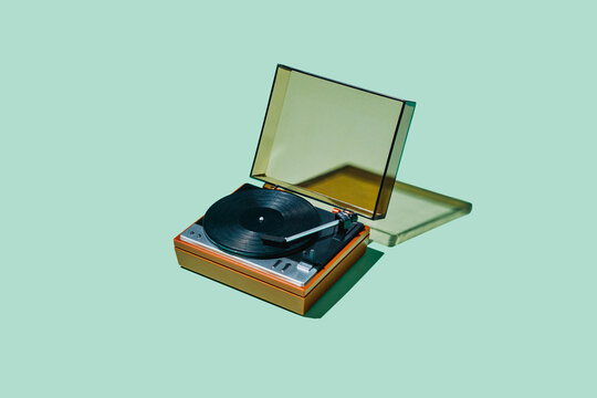 Vintage record player with translucent cover on mint green background
