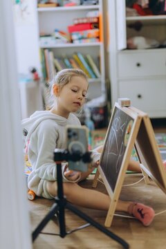 Child drawing on chalkboard at home with camera recording