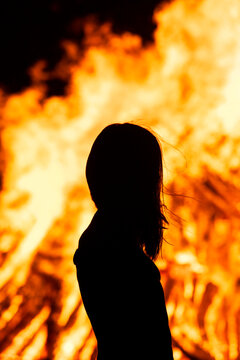 Woman silhouette in front of bonfire at solstice festival outdoors