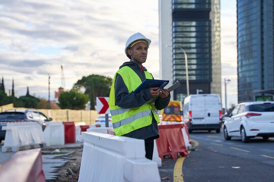 Construction supervisor with clipboard overseeing urban road project