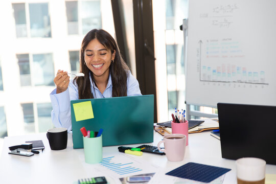 Employee eating yogurt at desk during break in modern office