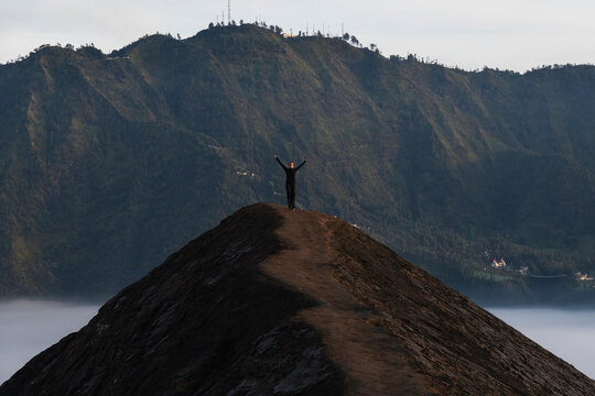 Woman standing on volcano summit at sunrise in Java Indonesia