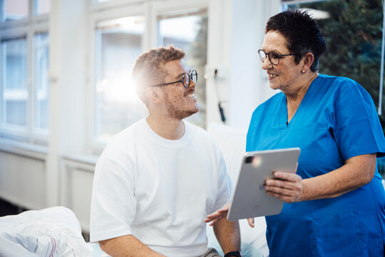 Doctor in medical uniform consulting patient with tablet in clinic