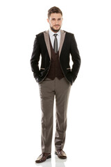 Fototapeta premium Full length portrait of a confident young businessman in a black suit, successful professional man standing and looking at camera with hands adjusting his jacket, isolated on white background.