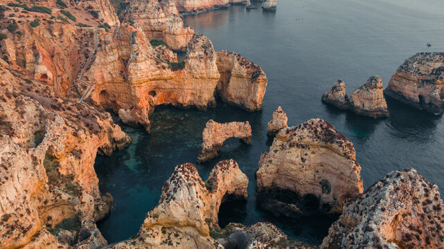 Aerial view of dramatic cliffs plunging into the turquoise sea, sculpted by time and tide, creating a stunning coastal panorama, Algarve, Faro District, Portugal.