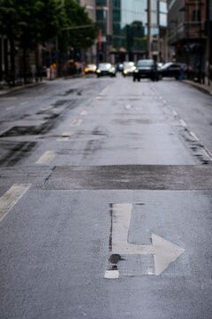 Wet urban road street asphalt with arrow direction markings in empty space creating navigation concept background for transport planning design