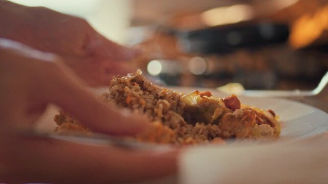 In warm home kitchen, young girl artfully arranges tender meat on plate, pairing it with steaming buckwheat porridge for a nourishing meal, embodying traditional comfort food and family cooking values