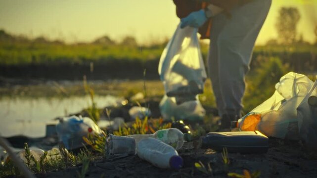 A human rights and climate advocate, a man diligently sorts discarded plastic bags and bottles on a serene pond shore at dusk, fostering plastic recycling and disposal
