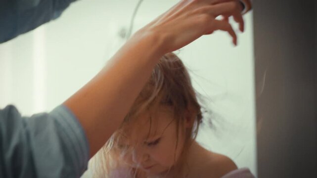 Tender mother gently dries her little one's wet hair with hairdryer at home, exuding warmth care in serene family setting, prioritizing child's comfort and safety amidst soothing domestic atmosphere