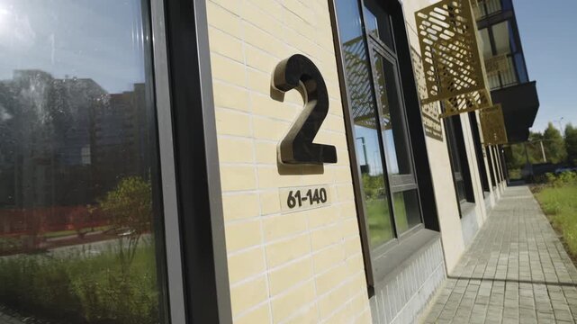 Large dimensional number marking residential entrance placed on wall. Lower section shows apartment numbering creating clear navigation