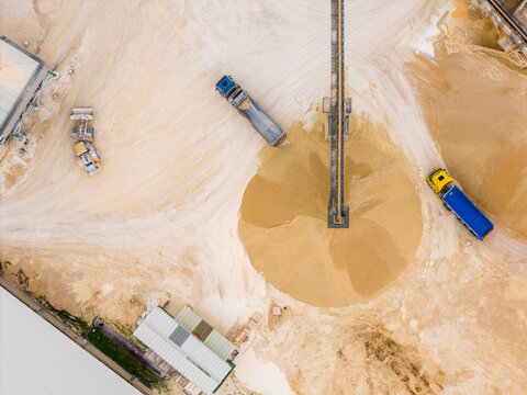 Aerial view of heavy machinery amidst beige sands and industrial structures creates a stark contrast of textures, Arsoli, Lazio, Italy.