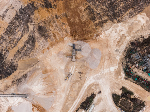 Aerial view of a vast, textured landscape carved by industry, where pale earth tones meet stark machinery, creating a scene of human intervention on a grand scale, Arsoli, Lazio, Italy.
