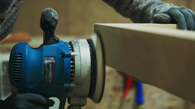 Professional carpenter polishing wood with orbital sander