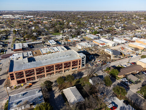 Aerial view of a massive brick building casting shadows over the streets below, contrasting with the bright sky, Frisco, Texas, United States.