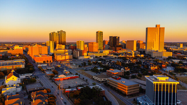 Aerial view of skyscrapers pierce the horizon as the setting sun casts a golden glow over the urban landscape, Fort Worth, Texas, United States.