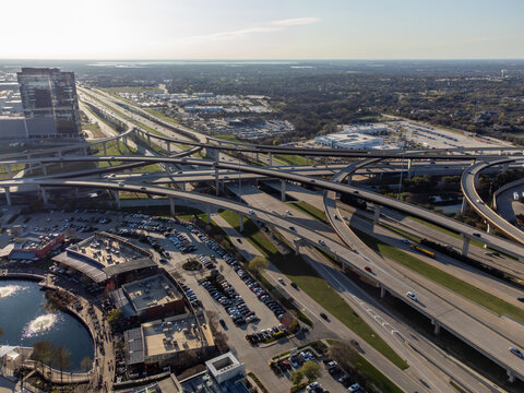 Aerial view of a complex highway interchange system with flyovers, connecting roads, and buildings, creating an intricate urban tapestry, Frisco, Texas, United States.