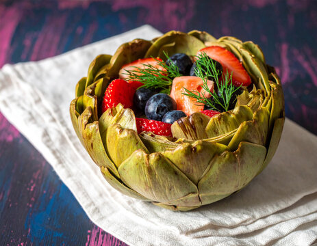 Artichoke filled with smoked salmon and fresh fruit on a napkin