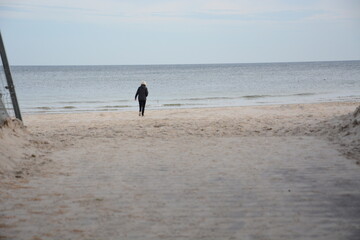 Osoba spacerujące nad samym morzem po plaży z widokiem na fale morskie © Marek