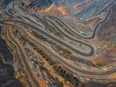 Aerial view of winding roads cutting through the layered, textured earth of the quarry, revealing a palette of grays, oranges, and browns, Kryvyi Rih, Dnipropetrovsk Oblast, Ukraine.