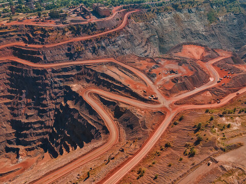 Aerial view of the stark, rust-colored earth cut away in terraces and winding roads, revealing the deep layers of Kryvyi Rih's mining landscape, Kryvyi Rih, Dnipropetrovsk Oblast, Ukraine.