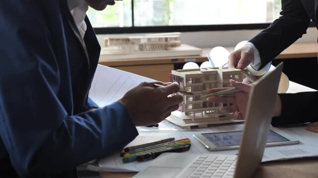 architects work on blueprints. Architects team brainstorming the design solutions with Architect Model. Architects and engineers team are working together to edit the draft plan that was designed.