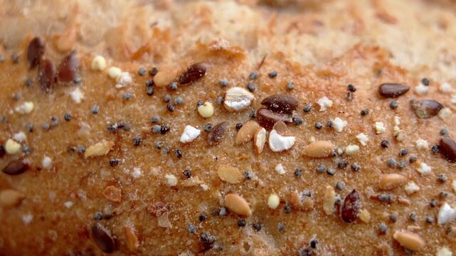 Whole grain bread surface topped with nutrient rich seeds and cereals. Natural food texture and healthy baking concept. Macro shot. Rotation
