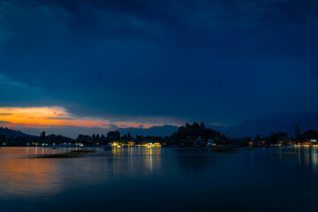 Obraz premium Sunset over Dal Lake with illuminated houseboats and mountain skyline, Srinagar, Kashmir