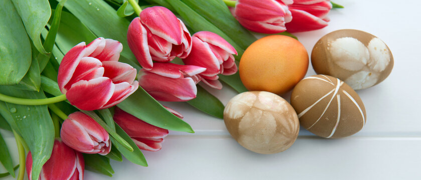 Easter background with bouquet of pink tulips and colorful eggs .