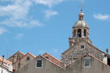 Obraz premium The ornate stone bell tower of Saint Marks Cathedral rises above traditional houses and terracotta rooftops in the historic old town of Korcula