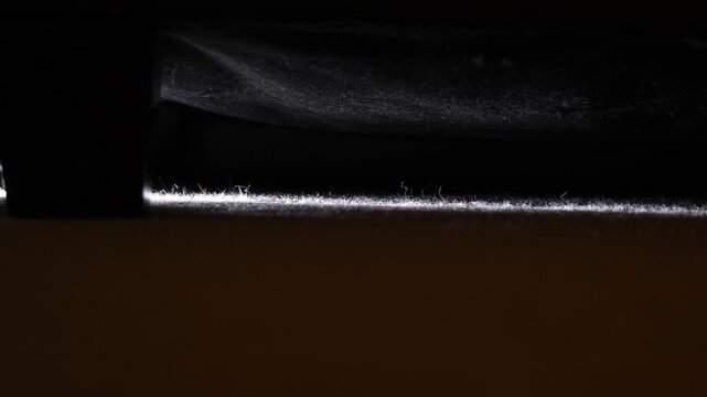 Close-up of a hand reaching for a remote control under a dark surface