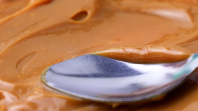 Sweet brown caramel toffee sauce spreading with a spoon close up