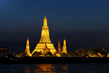 Naklejka premium Beautiful illuminated Wat Arun at twilight reflecting on the Chao Phraya River. A famous landmark of Bangkok, Thailand at night.