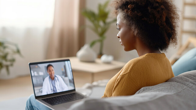 Young African American woman having a remote video call with doctor on her laptop at home. Modern telemedicine, online medical consultation and virtual healthcare service concept