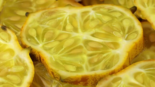 Kiwano fruit, African horned melon slices circle rotation close up. Organic orange kiwano pieces with seeds rotating