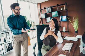 Business colleagues celebrate achievement in modern loft office with trophy award
