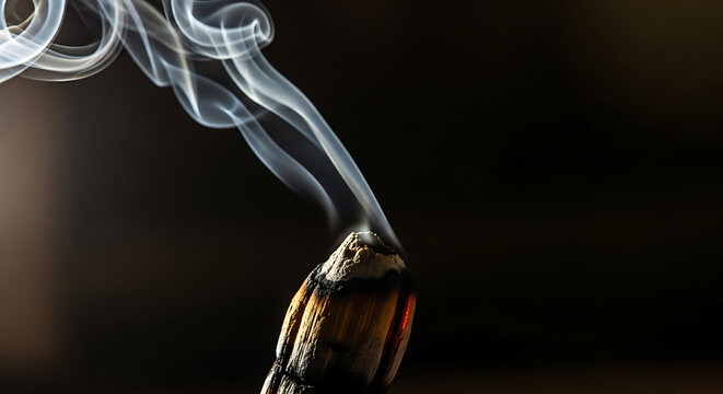 Close-up macro shot of smoke rising from a smoldering incense stick against a dark background