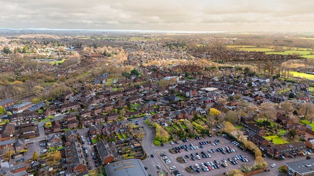 Landscape shot of Romsey, Hampshire with lush green vibrant fields in distance and overcast sunny spring skies at sunset with calm quiet roads below