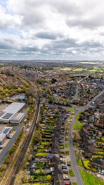 Portrait aerial drone shot overlooking Romsey, Hampshire with residential housing and railway track around quiet roads on overcast sunny spring day
