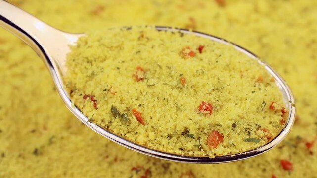Yellow chicken stock powder in a spoon with background circle rotation close up