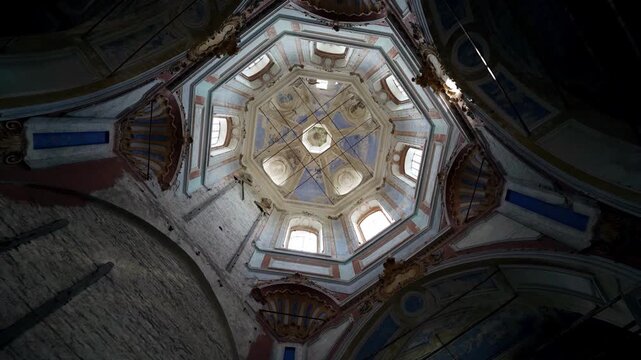 An old abandoned Christian church with a view from the inside. The aged frescoes and the light through the windows are visible