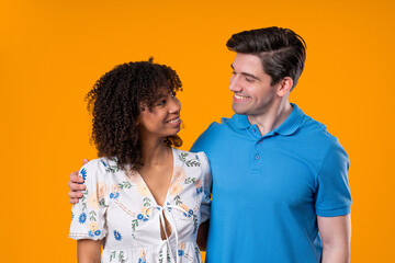 Fototapeta premium Happy Young Couple Smiling At Camera Standing Together On Yellow Studio Backdrop