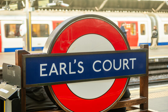 LONDON - Earls Court tube station &ndash; iconic roundel and platform sign with District line train