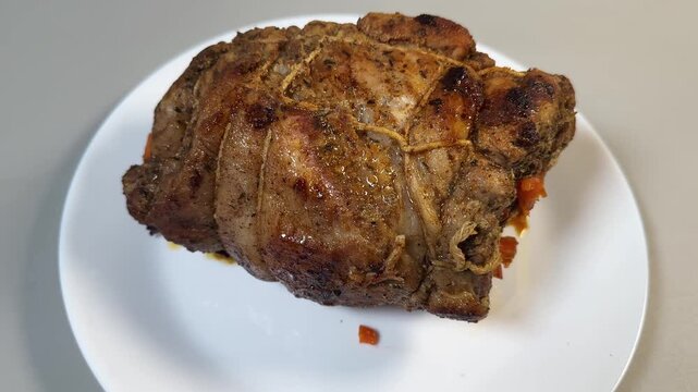 Baked pork neck with spices tied with twine on plate
