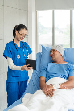 A male cancer patient on bed receives IV therapy while a female doctor offers care encouragement and updates on his test results providing support and discussing health progress