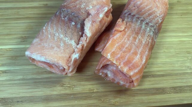 Raw frozen slices of salmon rolled up on cutting board