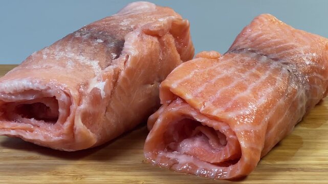 Raw frozen slices of salmon rolled up on cutting board
