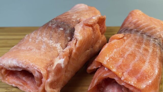 Raw frozen slices of salmon rolled up on cutting board