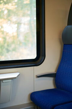 A blue train seat is adjacent to a large window with blurred green scenery outside. Zurich, Switzerland