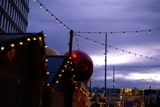 Evening market with string lights and red ornaments under a purple twilight sky. Zurich, Switzerland